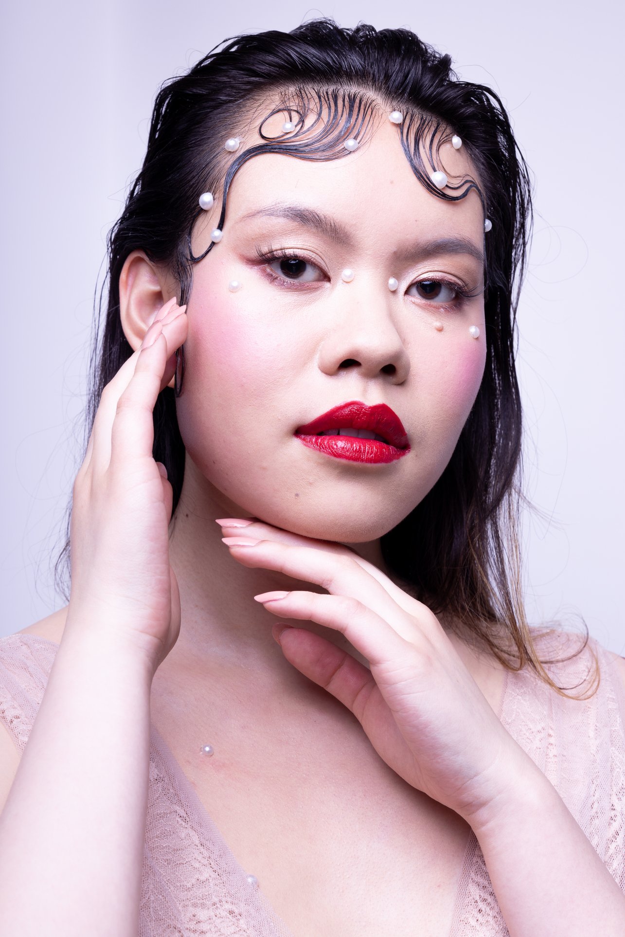 Editorial makeup on asian model. Sh is wearing flat pearls application around her oval paired with fresh cold pink blush and blue toned red lips.